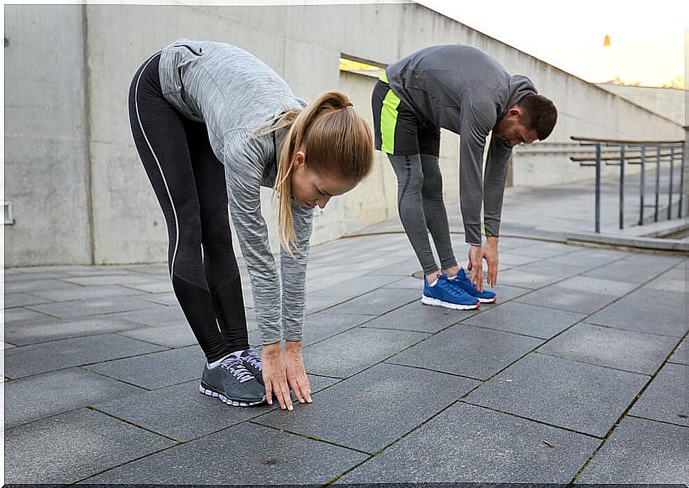 Woman and man stretching their legs with hands on the floor