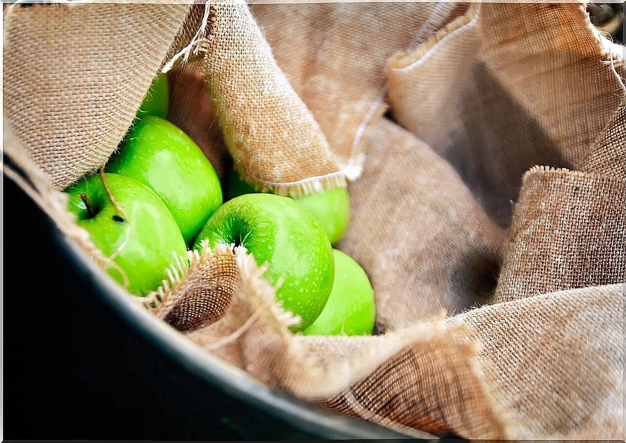 Green apples in a basket with cloth.