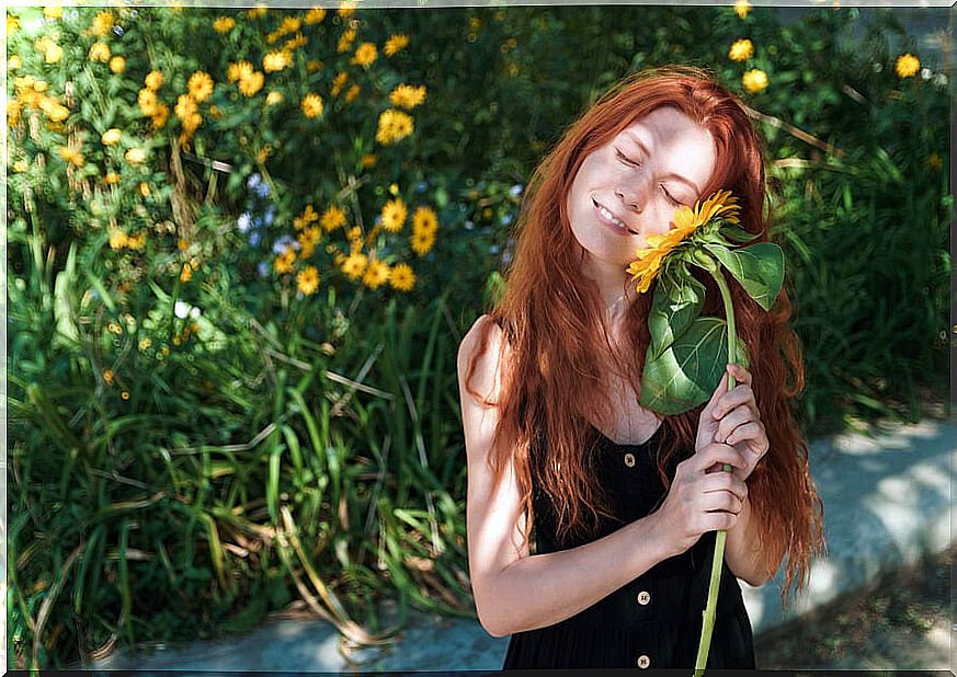 Woman smiling with a sunflower in her hand happy.