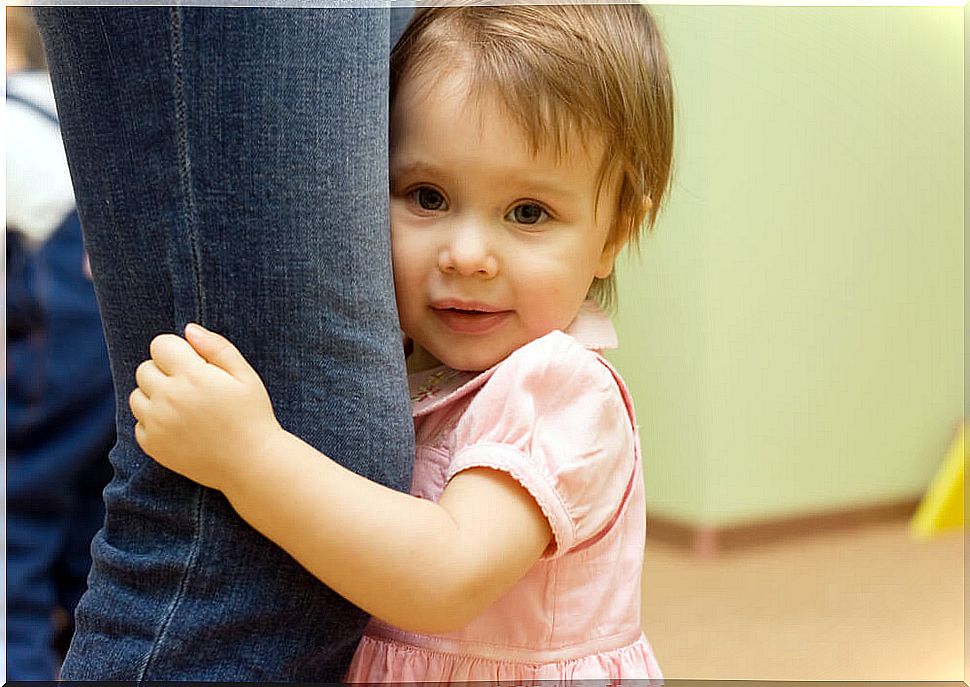 Little girl clinging to her mother's leg