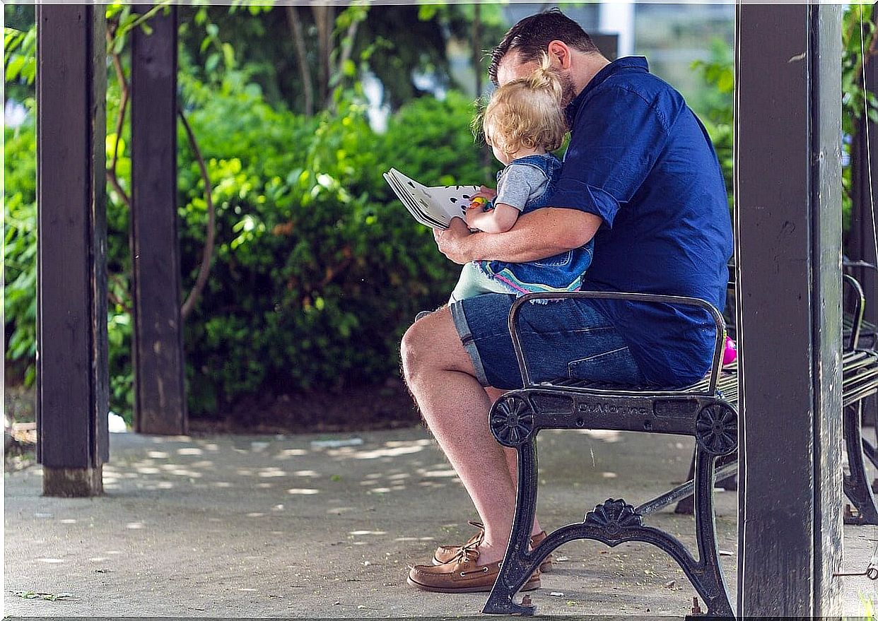 Father teaching his son to read at an early age in the park.