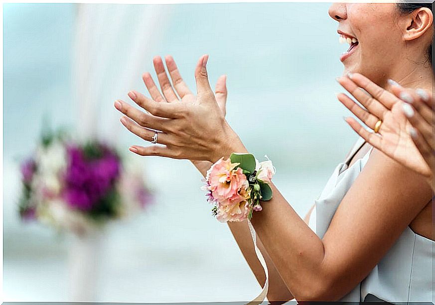 Wedding guest clapping with a flower on her arm