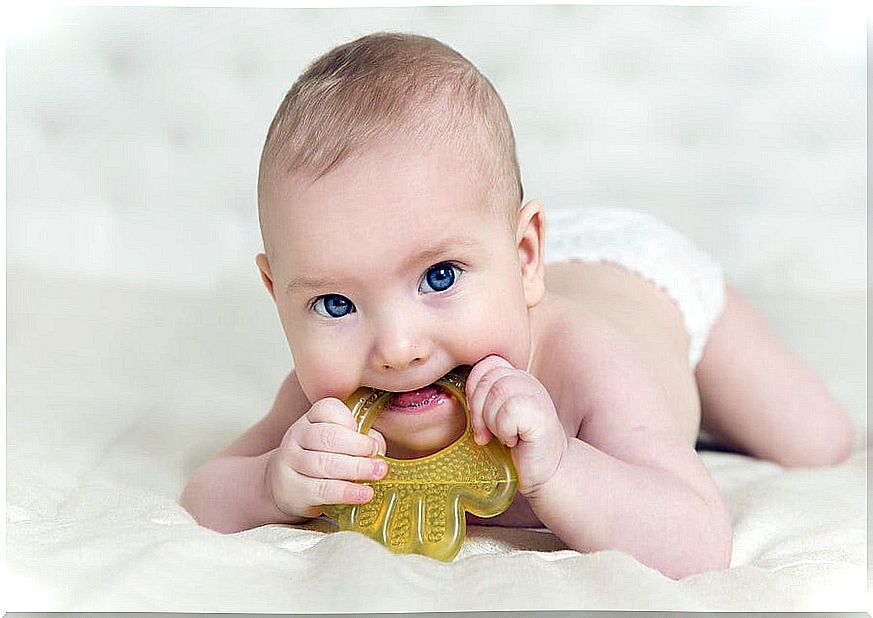 Baby with a teether in his mouth.