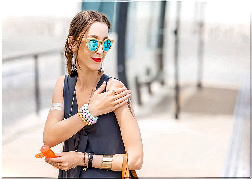 Woman walking through the city putting on sunscreen