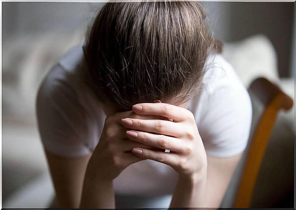 Overwhelmed girl covering her face with her hands.