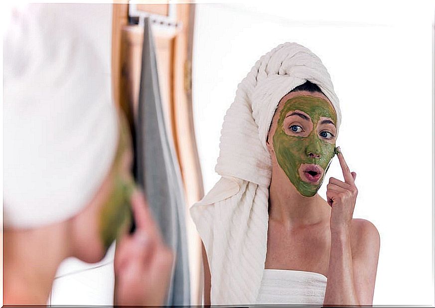 Woman applying green tea mask to treat acne